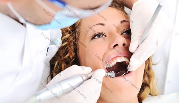 A woman getting her teeth cleaned by dentist.