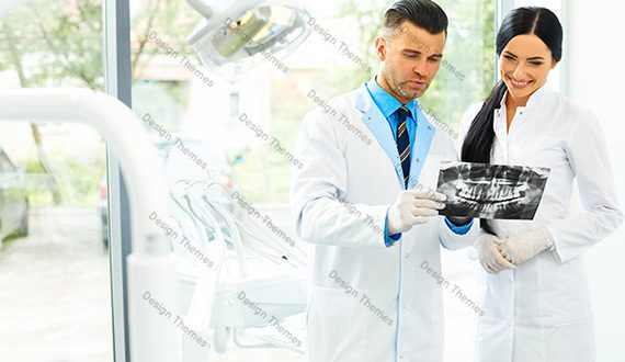 A man in white lab coat holding a camera.