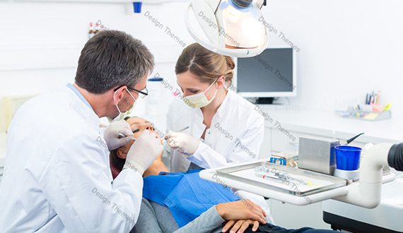 A dentist and two assistants working on a patient.