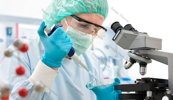A person in a lab coat and goggles is using a microscope.