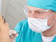 A surgeon is examining the patient 's ear.