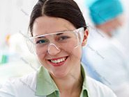 A woman wearing safety glasses and smiling.
