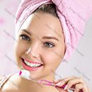 A woman with pink towel on her head is brushing her teeth