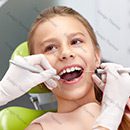 A girl is getting her teeth checked by an dentist.