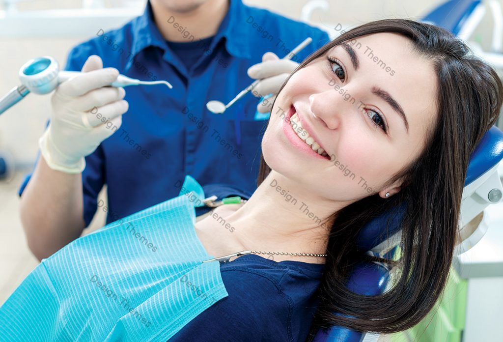 A woman smiles while sitting in the dentist 's chair.