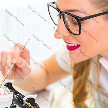 A woman with glasses is painting something on the table.