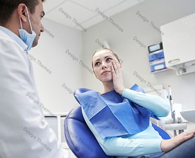 A woman sitting in front of a dentist.