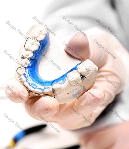 A person holding an artificial teeth in their hand.