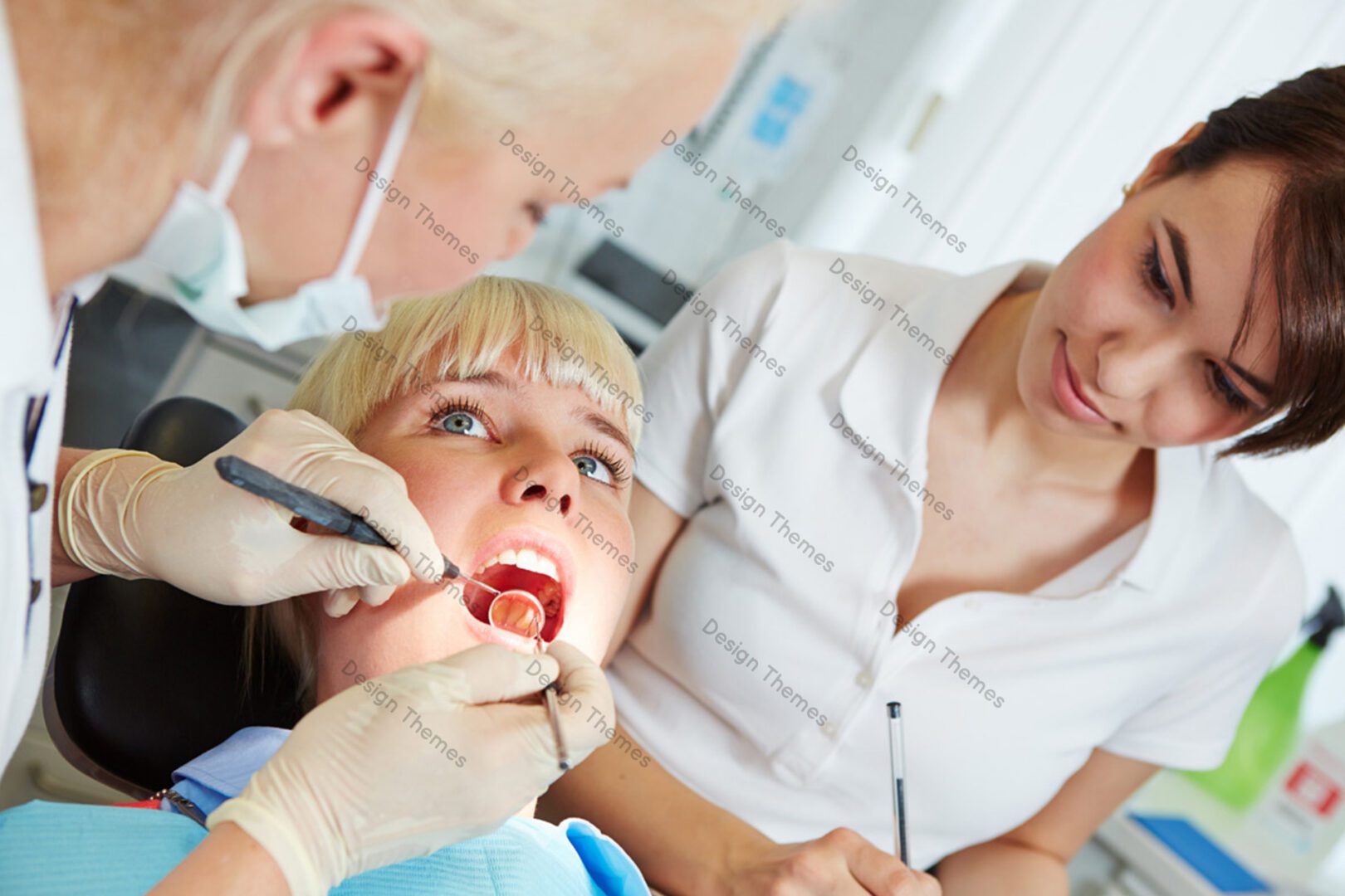 A woman getting her teeth checked by two dentists.