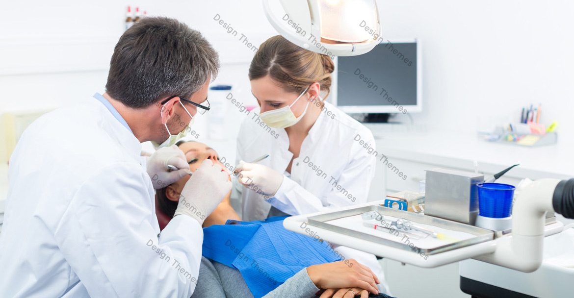 A dentist and two assistants working on a patient.