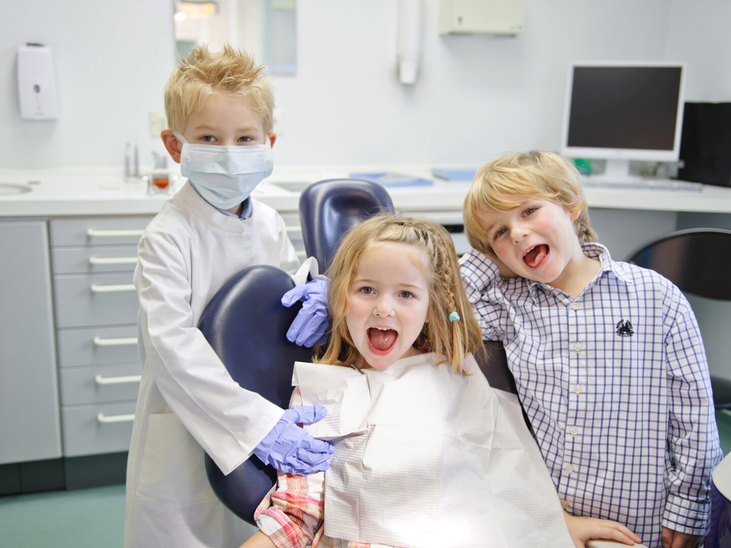 Three children sitting in a dentist chair with their teeth.