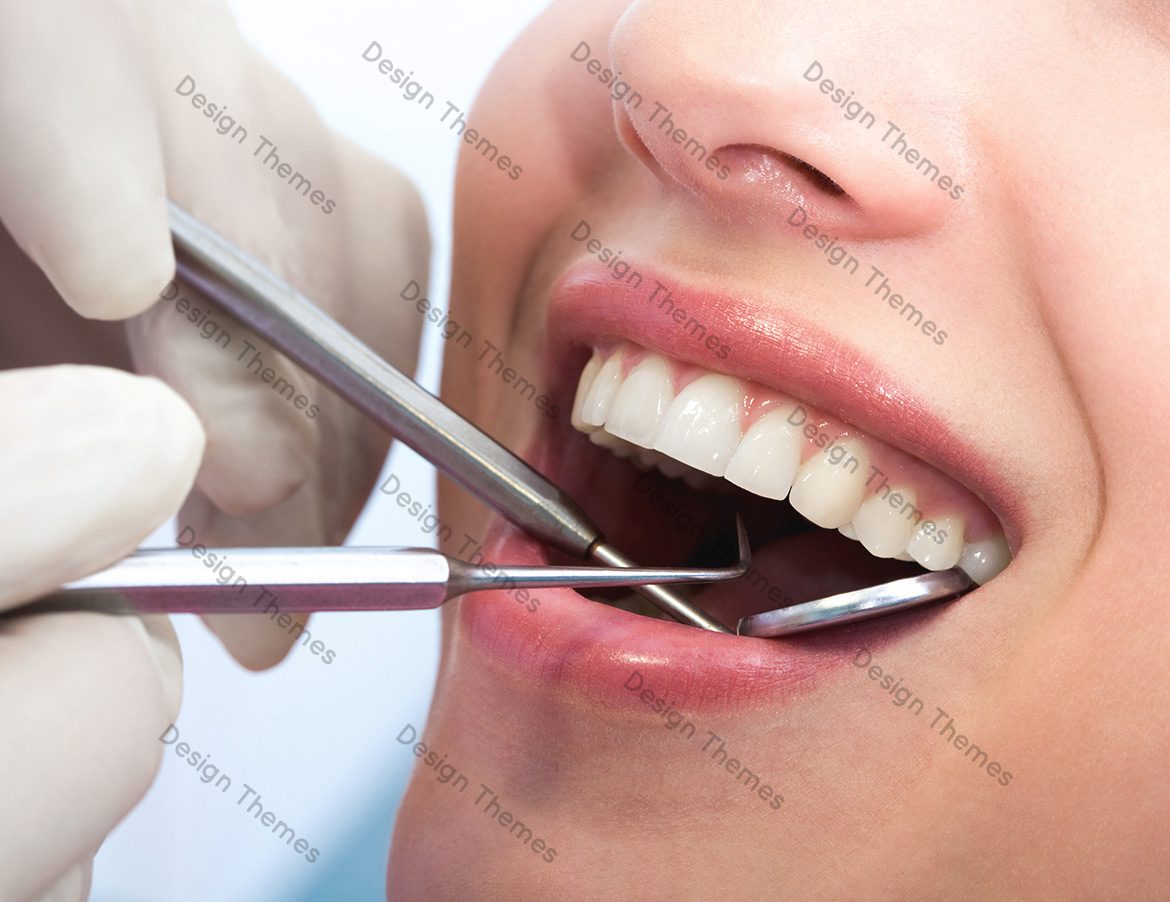A woman getting her teeth cleaned by dentist.