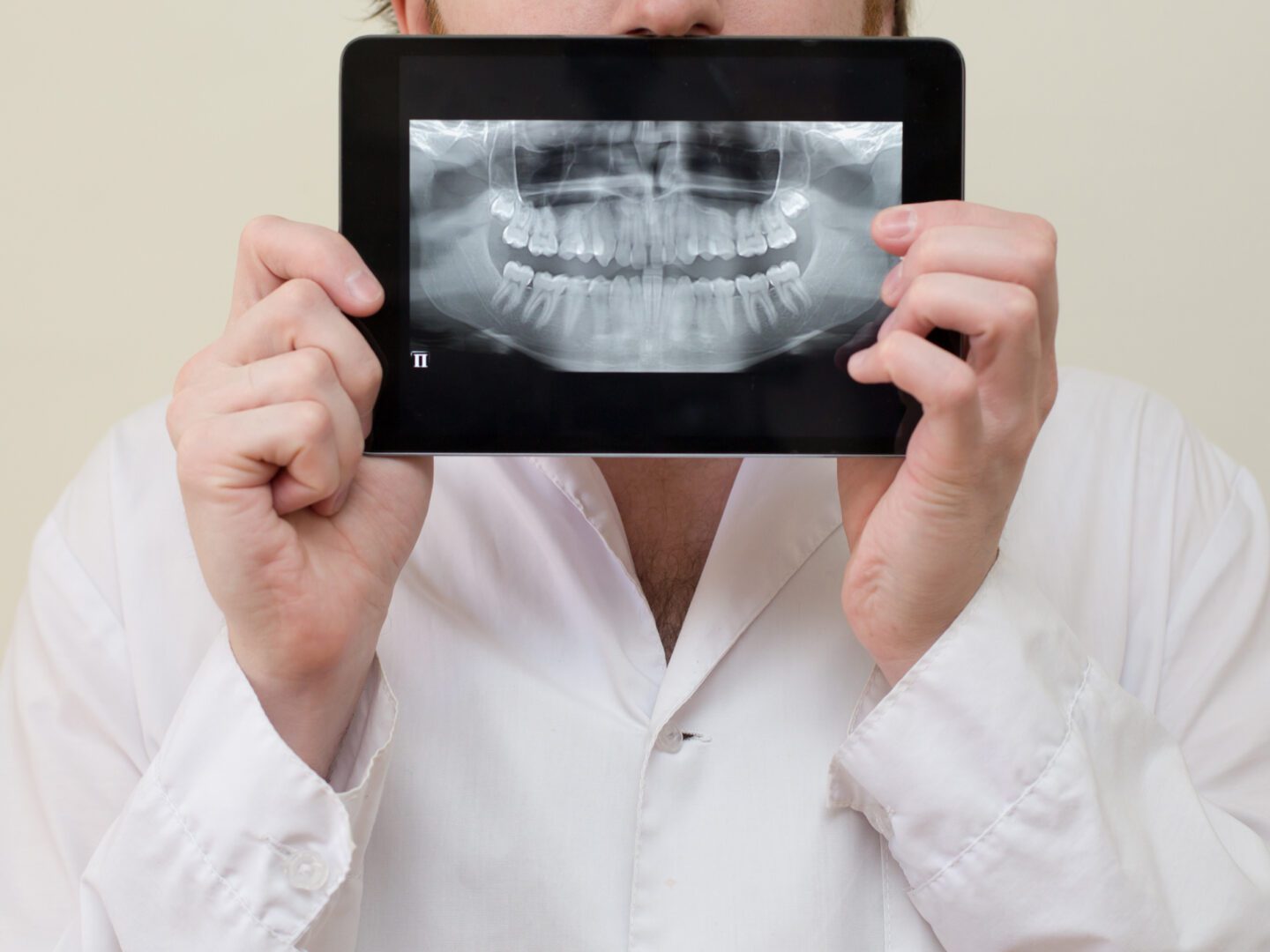 A man holding up an ipad with a picture of teeth.